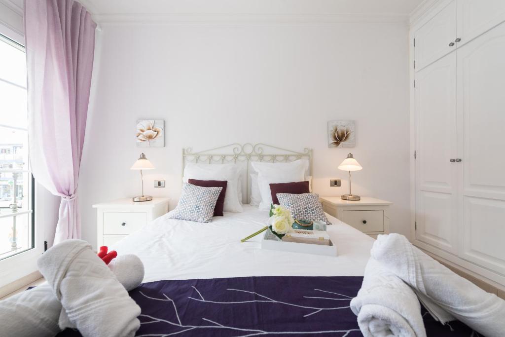 Un dormitorio blanco con una cama con toallas. en Mogan Beach | CarmitAtHome, en Puerto de Mogán
