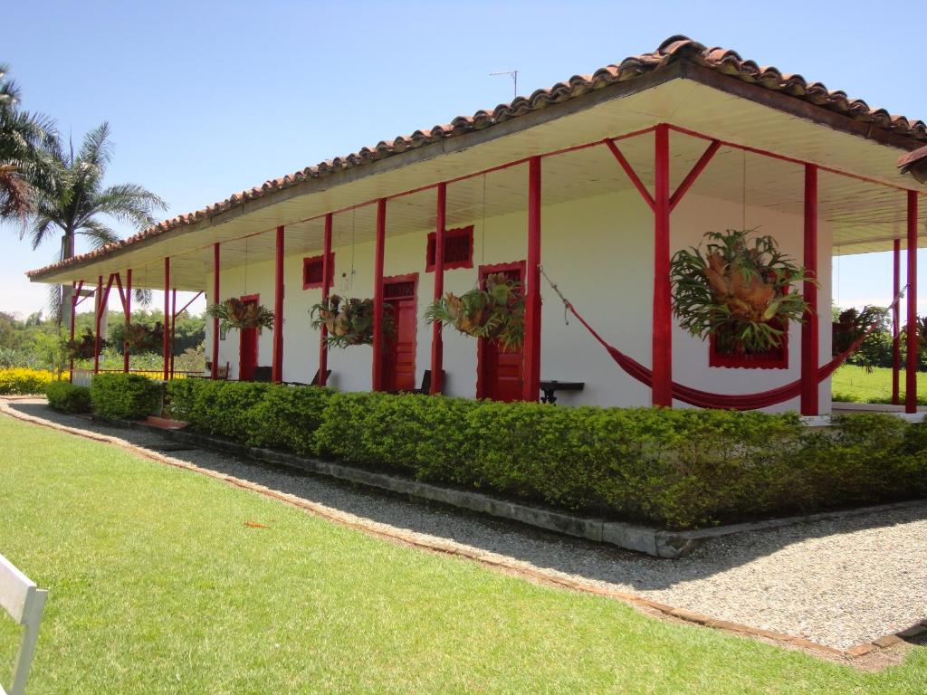 ein weißes Gebäude mit roter Ausstattung im Hof in der Unterkunft Finca Hotel Santana Campestre in Quimbaya