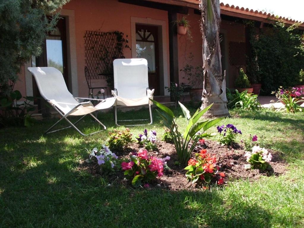 two chairs and flowers in the yard of a house at Villa Cristina in Syracuse