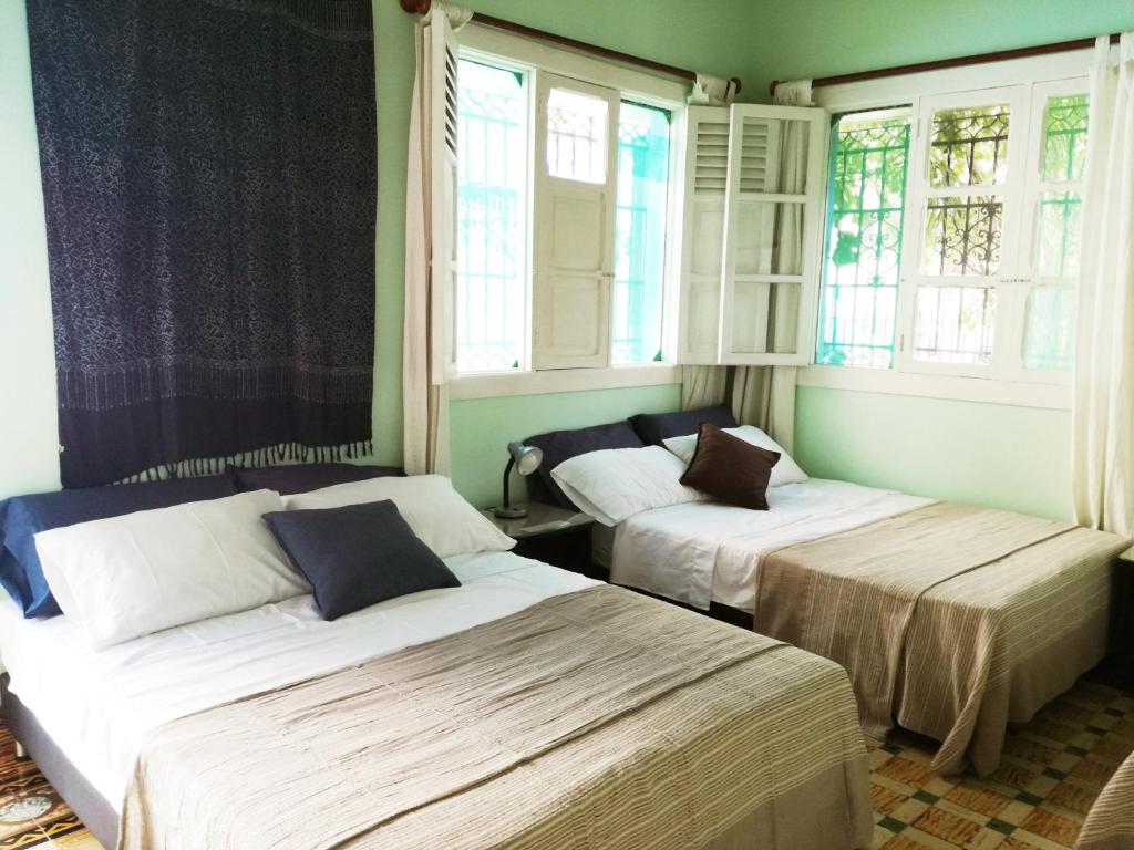 two beds sitting in a room with windows at La casa azul in Cartagena de Indias