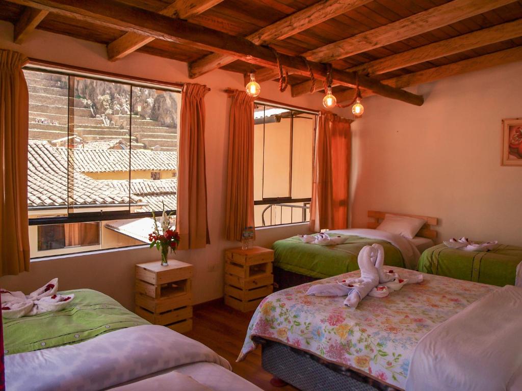 a bedroom with three beds with stuffed animals on them at Eureka Lodge in Ollantaytambo