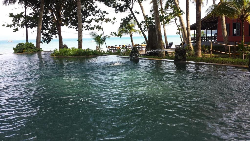 einen Pool mit Palmen und dem Meer in der Unterkunft Kuda Laut Resort in Cisolok