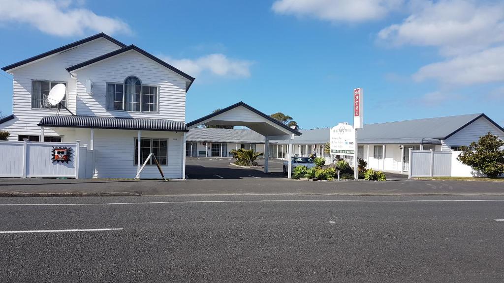 a white house on the side of a street at Blake Court Motel in Whangamata