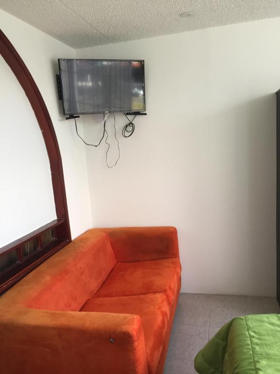 un sofá naranja en una habitación con TV en la pared en Apt estudio calle97302, en Bogotá