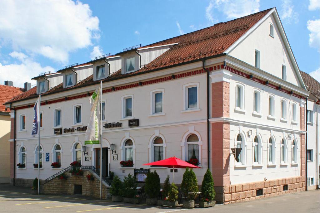 un bâtiment avec un parapluie rouge devant lui dans l'établissement Hotel Rössle, à Trochtelfingen