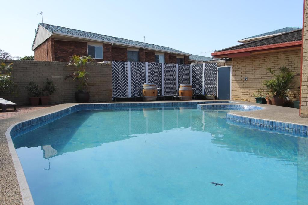 a large blue swimming pool in front of a house at Toreador Motel in Coffs Harbour