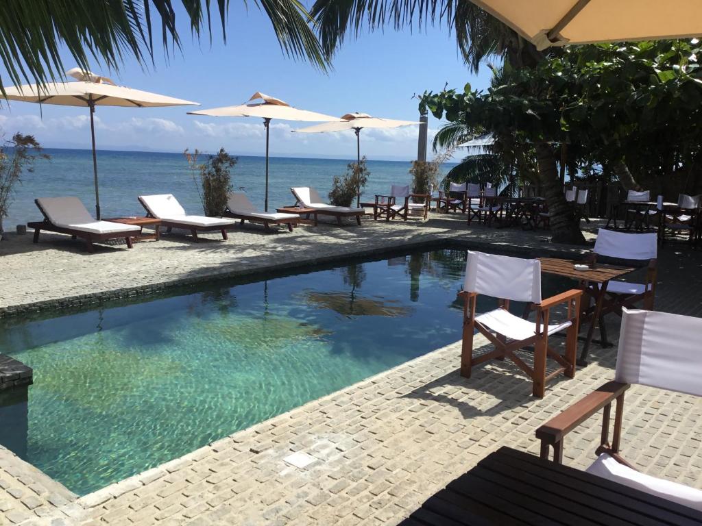 a swimming pool with chairs and umbrellas next to the ocean at Idylle Beach in Sainte Marie