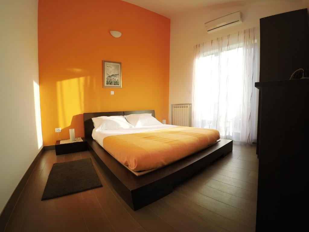 een slaapkamer met een bed met een oranje muur bij apartman Adriana 3 - kat in Poreč