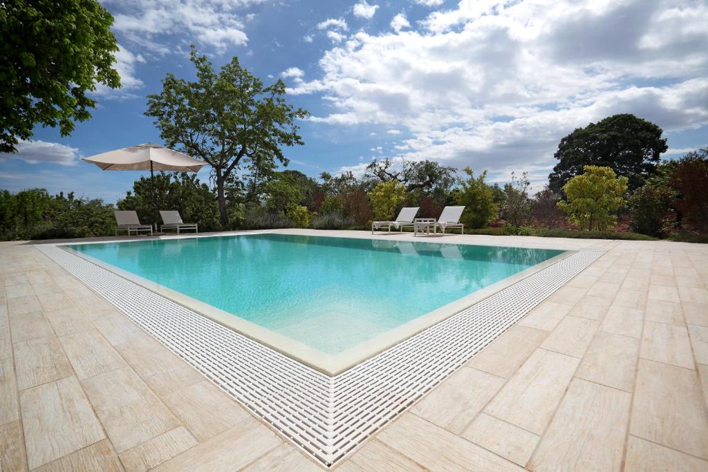 a swimming pool with chairs and an umbrella at Villa Aurelia in Castellana Grotte