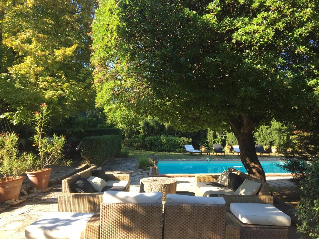a patio with couches and a tree next to a pool at LA BERGERIE, ROCBARON in Rocbaron