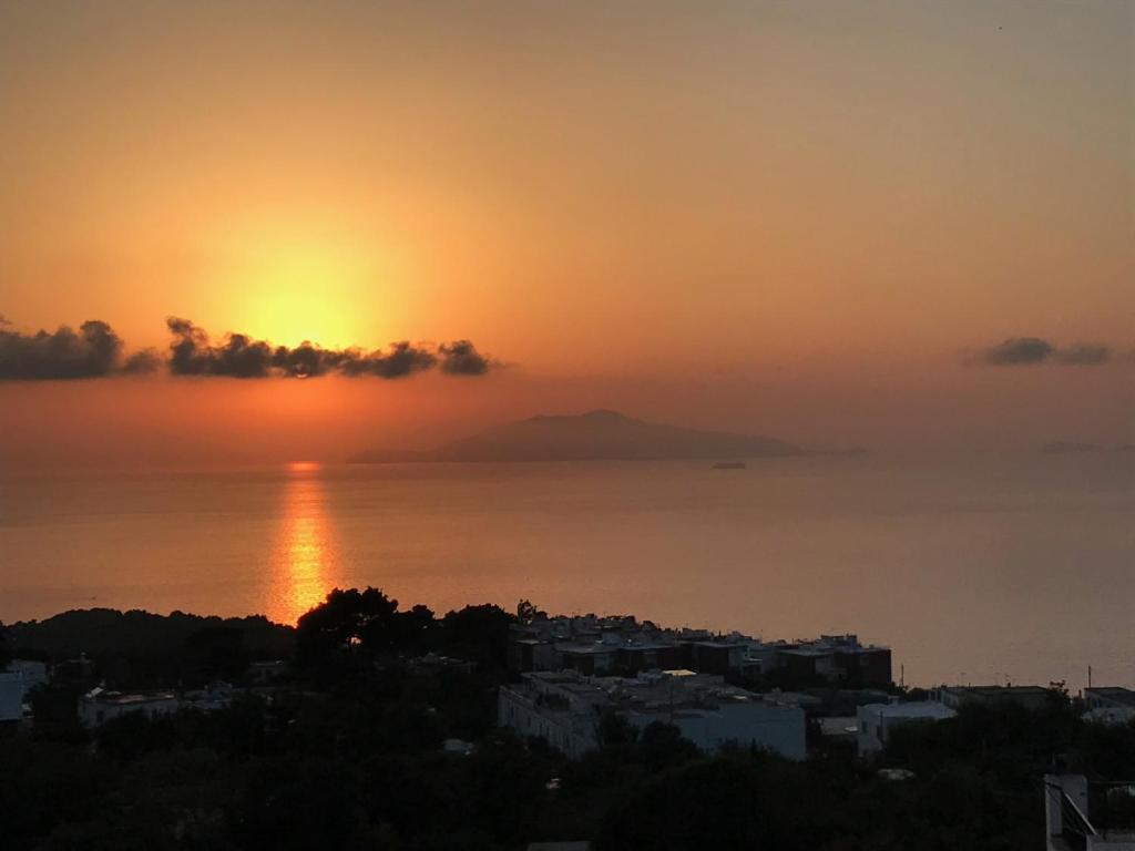 a sunset over the ocean with a city in the foreground at R&D Rest and Dream Capri in Anacapri