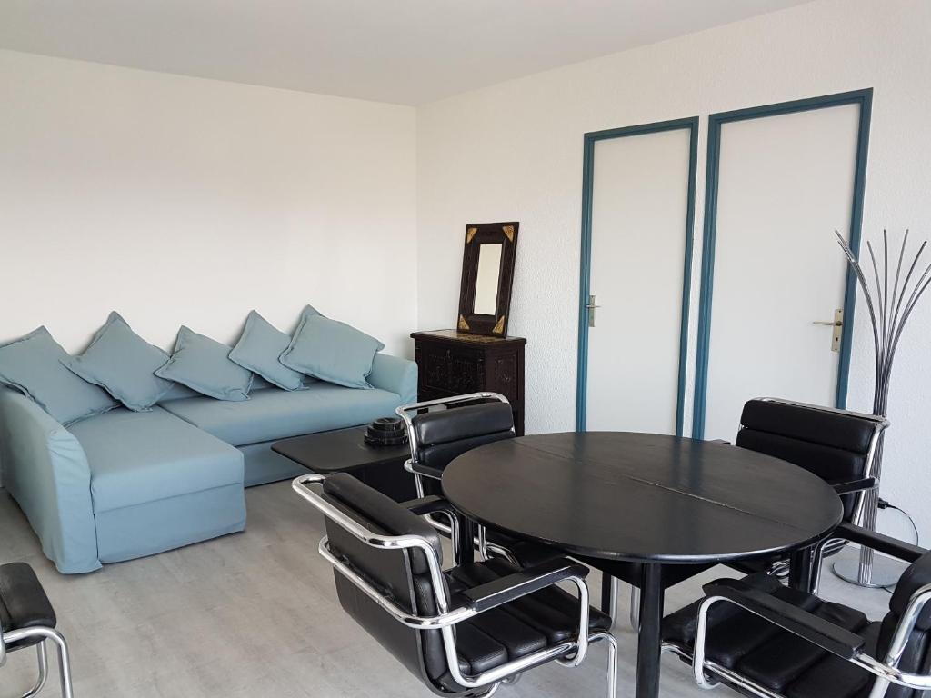 a living room with a couch and a table and chairs at Réf 542 Seignosse océan , bel appartement avec parking privatif, à 250m de la plage, 5 personnes in Seignosse