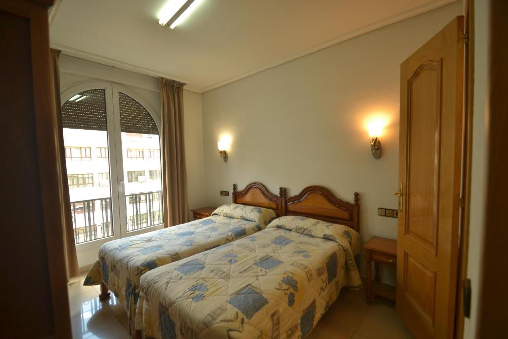 sypialnia z łóżkiem i dużym oknem w obiekcie Hostal Retiro w Madrycie