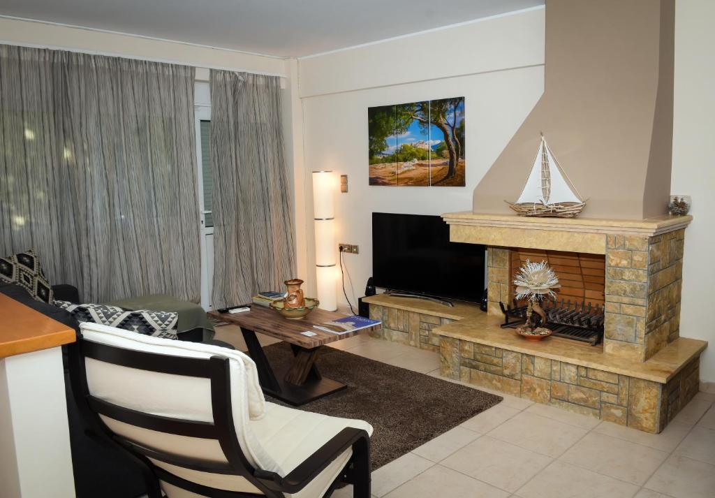 salon z kominkiem i telewizorem w obiekcie Cozy Apartments near the airport w mieście Artemida