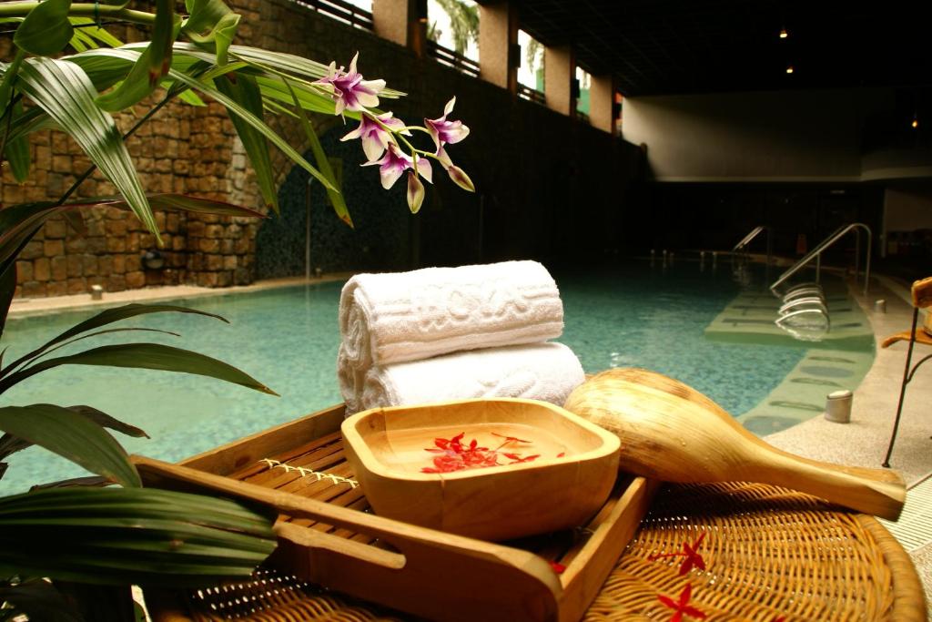 een dienblad met handdoeken en een kom water naast een zwembad bij Hoya Hot Springs Resort & Spa in Wenquan