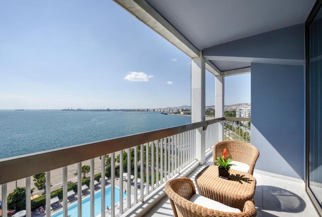 a balcony with two chairs and a view of the water at Makedonia Palace in Thessaloniki