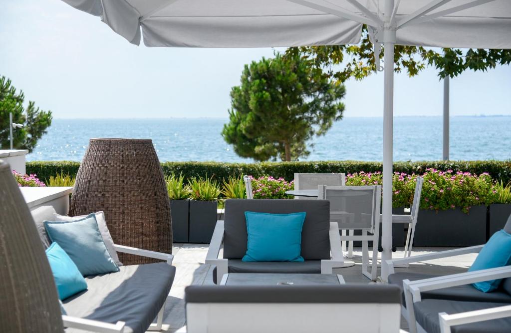 a patio with chairs and an umbrella and the ocean at Makedonia Palace in Thessaloniki