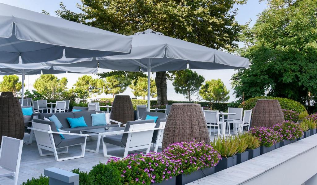 a patio with white chairs and tables and an umbrella at Makedonia Palace in Thessaloniki