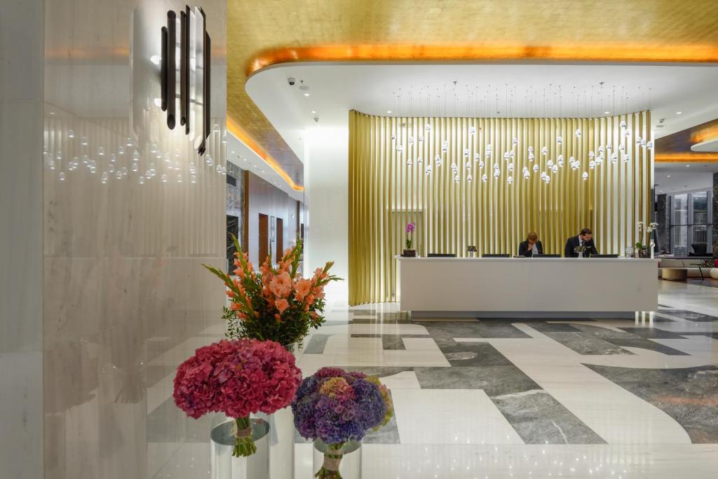 a lobby with flowers in vases on a table at Makedonia Palace in Thessaloniki