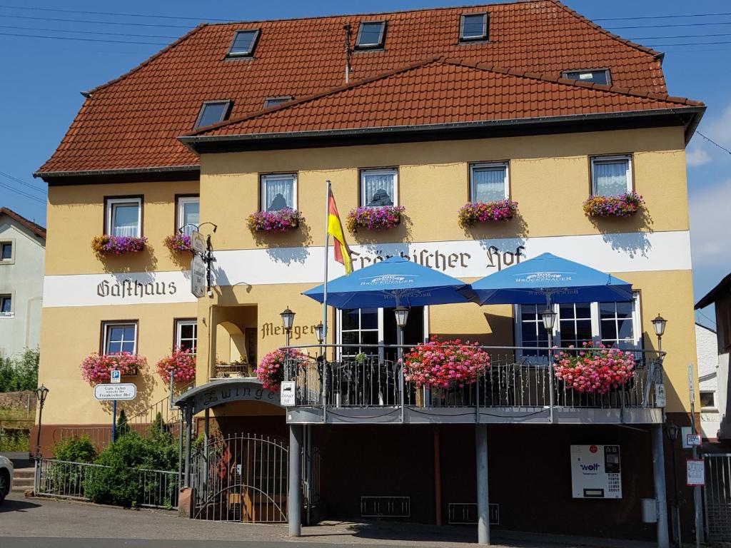 a yellow building with a blue umbrella in front of it at Fraenkischer Hof in Zeitlofs