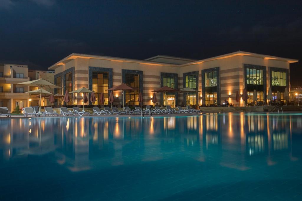 a large building with a swimming pool at night at Aura Resort Sidi Abd El Rahman El Alamein in Sīdī ‘Abd ar Raḩmān