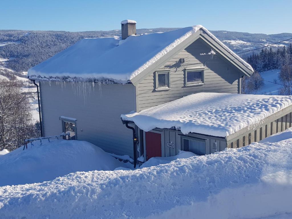a house covered in snow with a roof at Lille Randklev Gæstehus in Ringebu