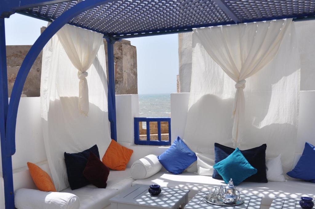 a living room with a white couch with colorful pillows at Riad le Consulat - Riad privé avec services in Essaouira