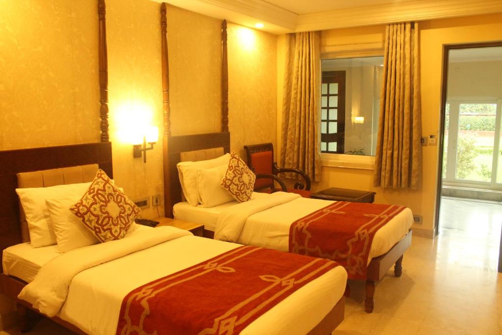 a hotel room with two beds and a window at Hotel Surya, Kaiser Palace in Varanasi