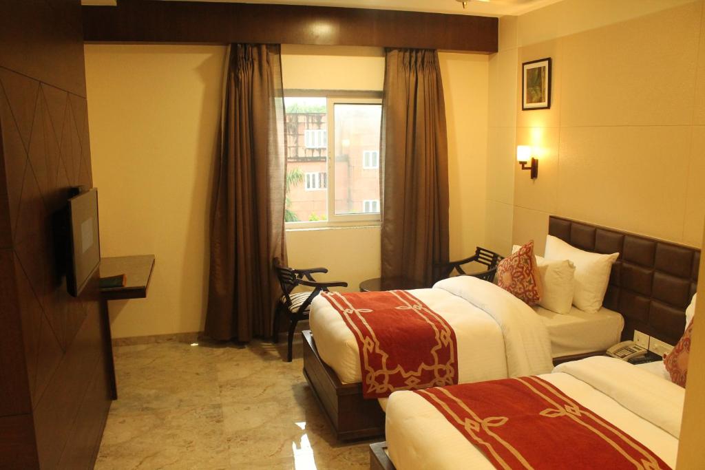 a hotel room with two beds and a television at Hotel Surya, Kaiser Palace in Varanasi