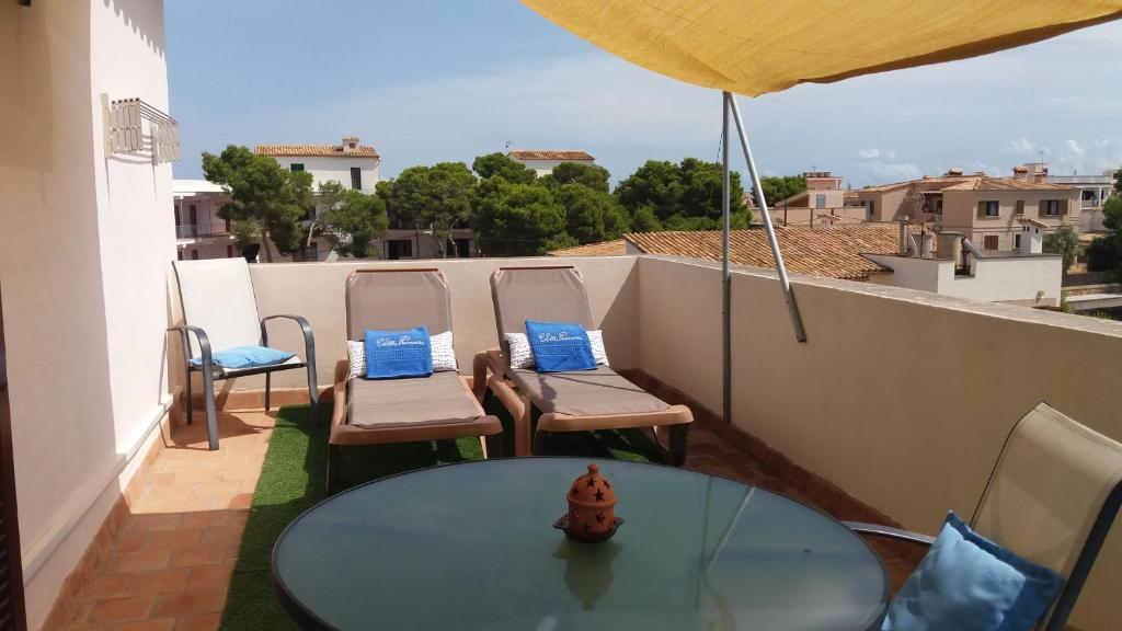 a patio with a glass table and chairs on a balcony at Apartamentos Villa Primera in Cala Figuera