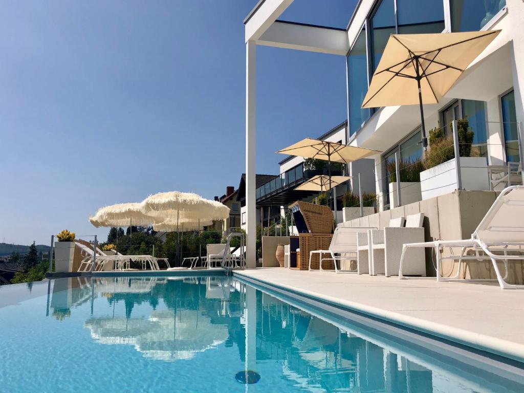 梅靈的住宿－奧林格酒莊-公寓式酒店，一座带椅子和遮阳伞的游泳池位于一座建筑旁边