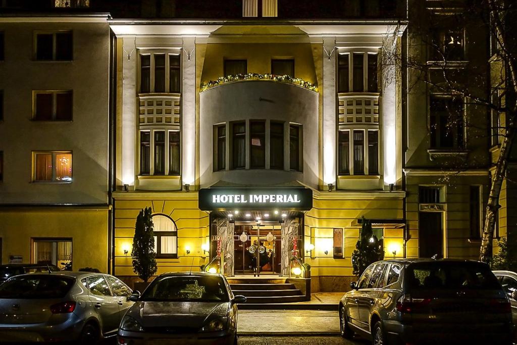 Un hotel con coches aparcados delante por la noche. en Hotel Imperial, en Colonia