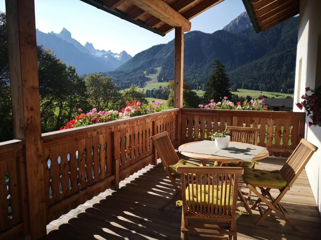 a wooden deck with a table and chairs and mountains at Peterlan Hof in Dobbiaco
