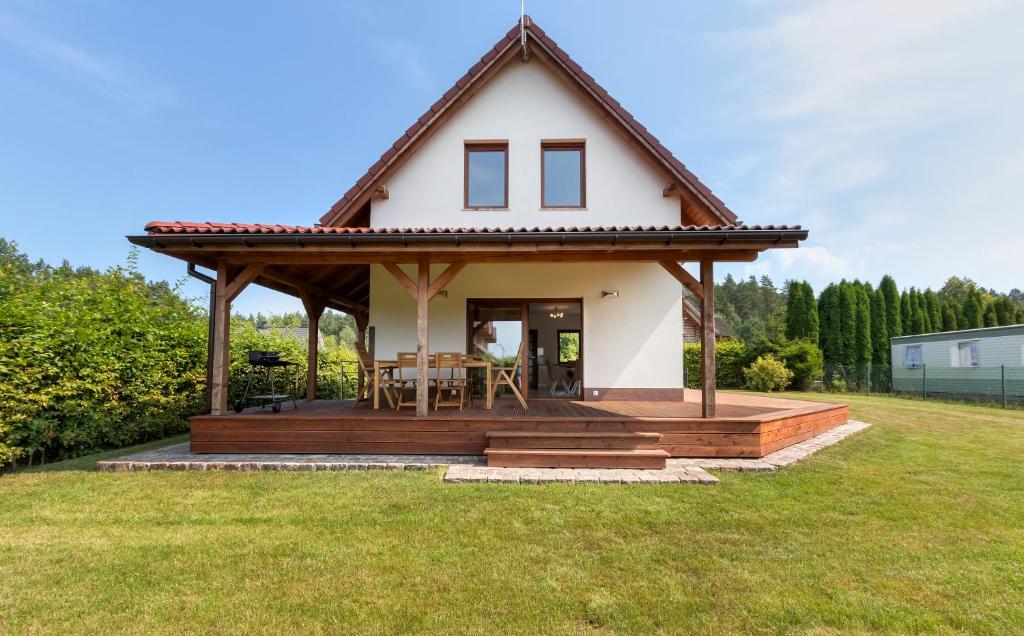 a small white house with a wooden deck at Amber House in Wisełka