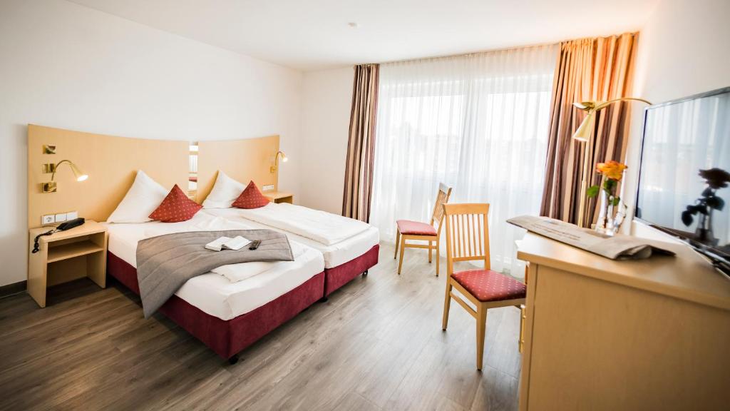 ノイウルムにあるCity-Hotel garniのベッドとデスクが備わるホテルルームです。