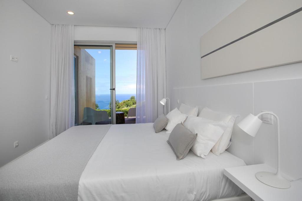 a white bedroom with a large white bed with white pillows at Mosteiros Place in Mosteiros