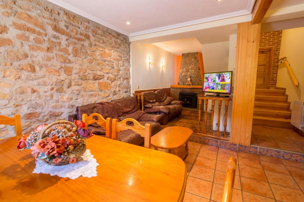 sala de estar con mesa y pared de piedra en Casa Rural Cañón de Río Lobos II en Casarejos