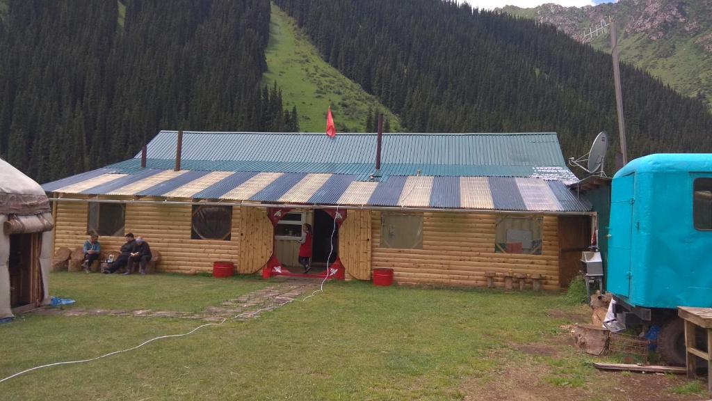 a log cabin with people sitting outside of it at Ala-Kul guesthouse in Altyn-Arashan in Karakol