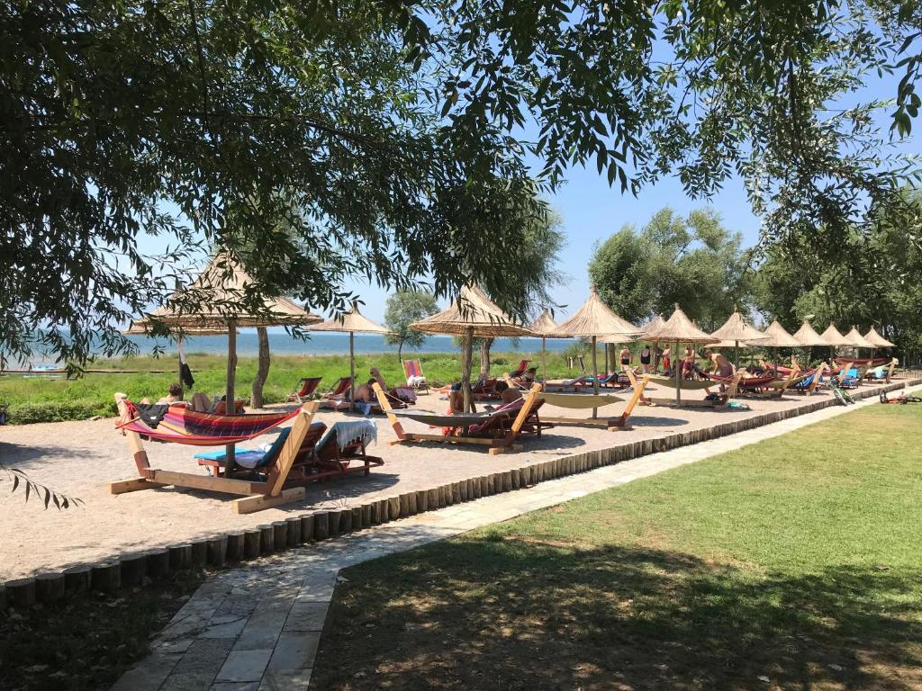 people sitting on benches in a park at Lake Shkodra Resort in Grilë