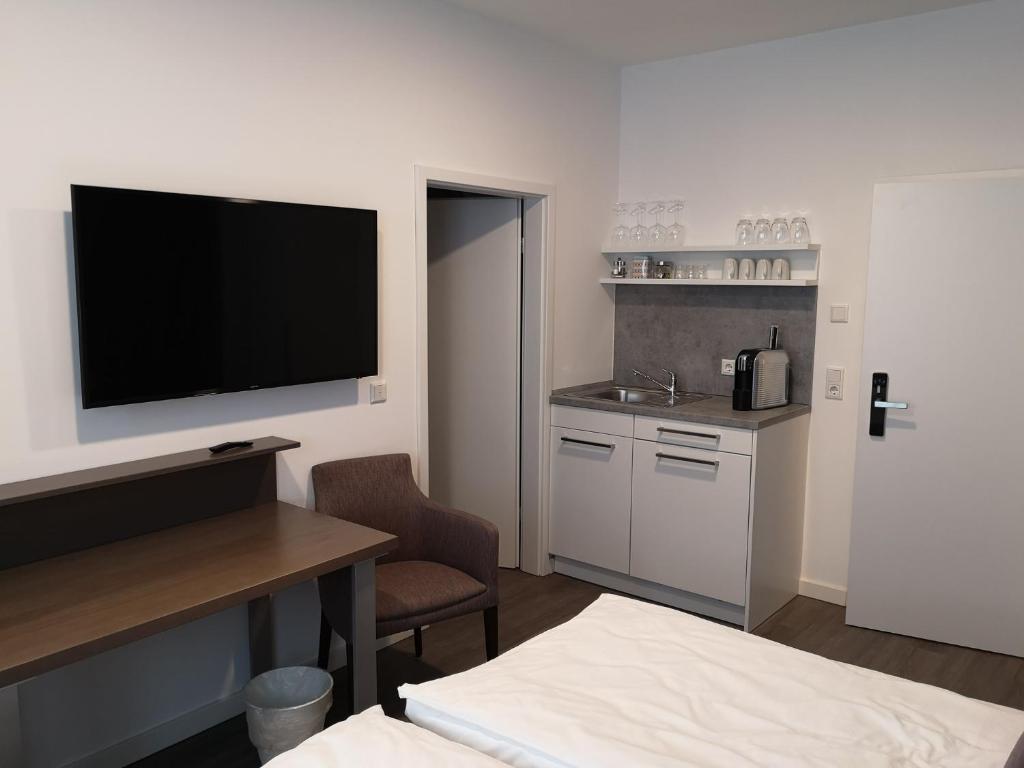 Zimmer mit einem TV und einer Küche mit einem Tisch. in der Unterkunft Trip Inn PostApart Aschaffenburg in Aschaffenburg