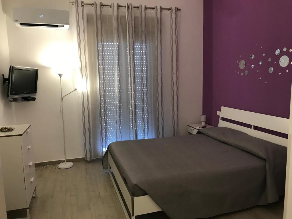 a bedroom with a bed and a tv and purple walls at Appartamento Le Tre Rose in Trapani