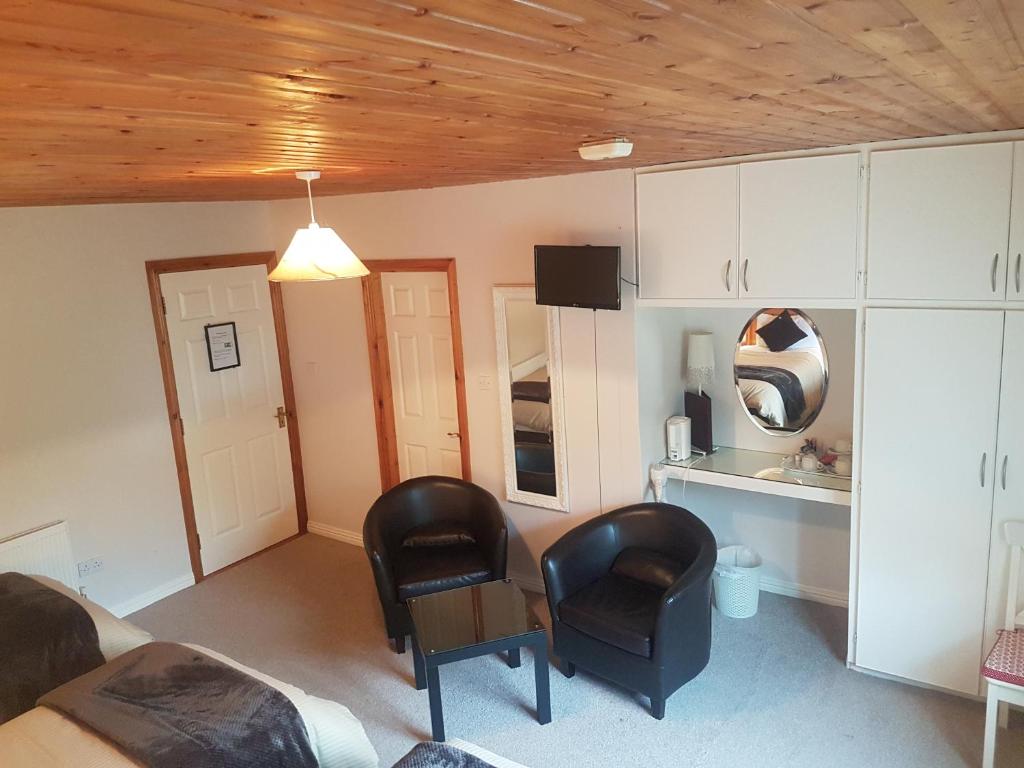 a living room with two chairs and a kitchen at Ben Breen House B&B in Clifden