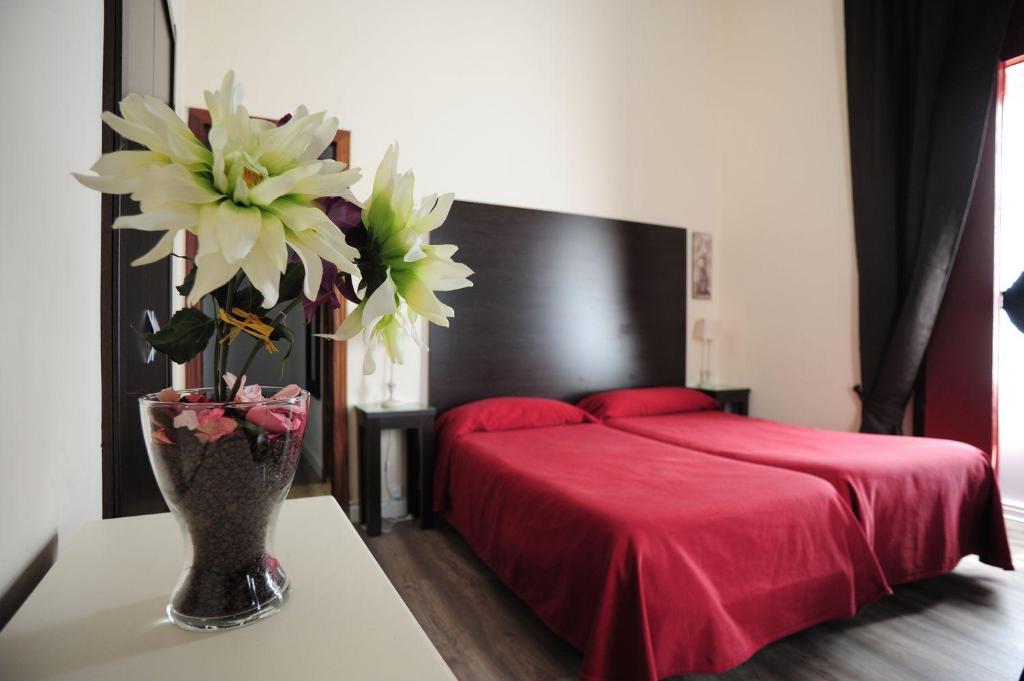 a bedroom with a red bed and a vase with flowers at Hospederia Marqués in Cádiz