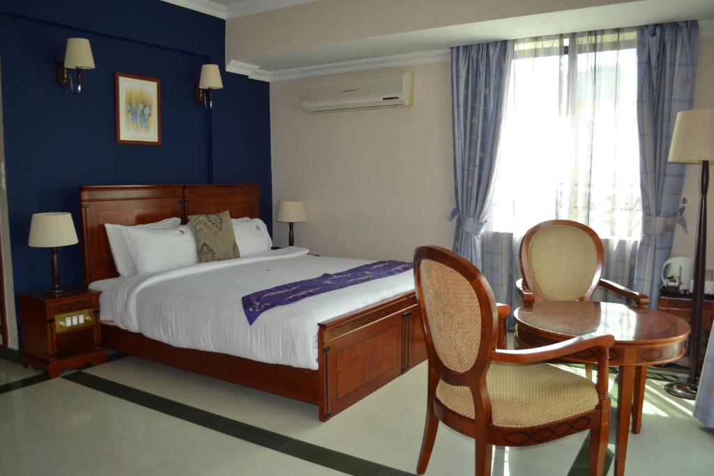 a bedroom with a bed and a desk and a chair at Hotel Nikko Towers in Dar es Salaam