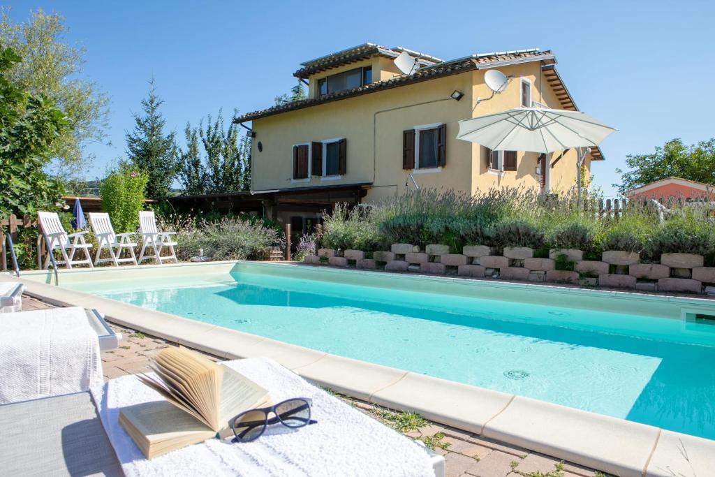 a swimming pool with chairs and a house at Country House Villa Sabrina in San Ginesio