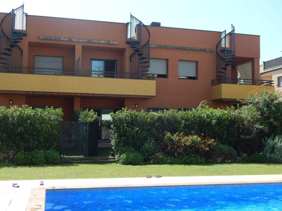 a building with a swimming pool in front of a house at Masia Blanca - Coma-ruga in Comarruga