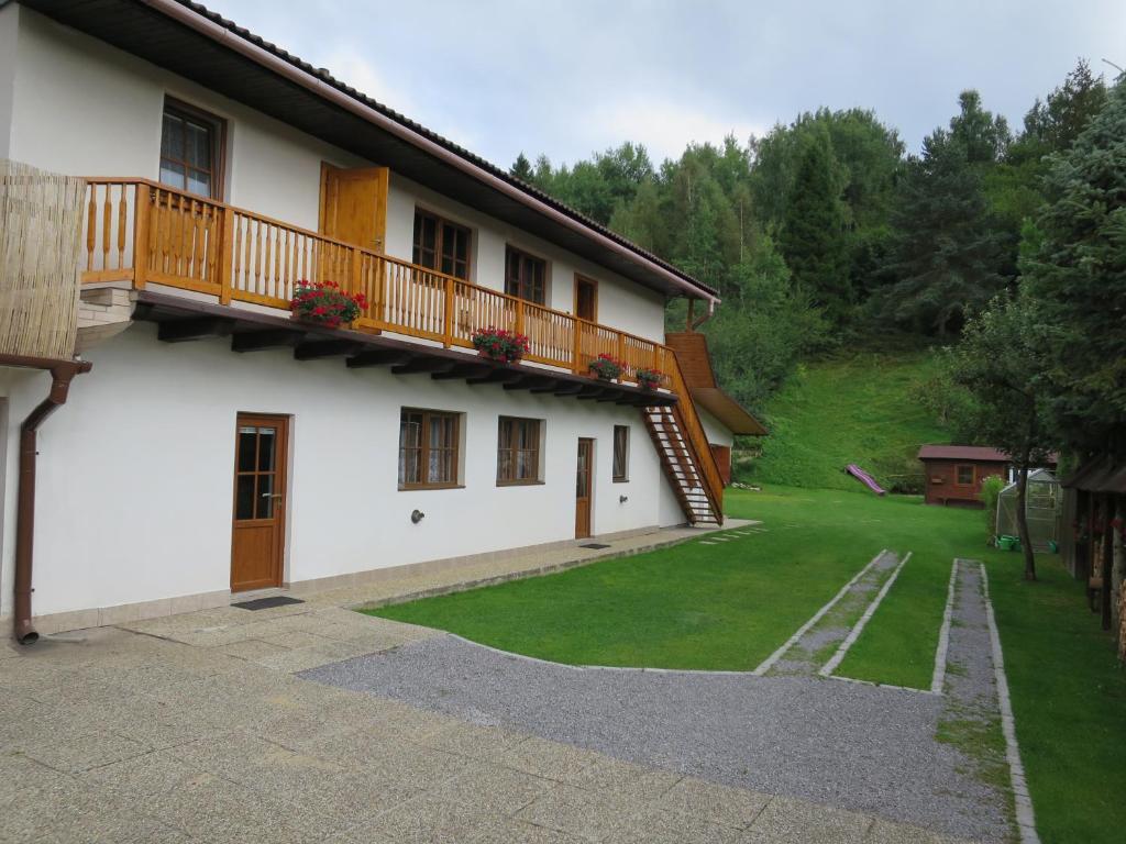 a white house with a balcony and a yard at Apartmány pri Studničke in Oravský Biely Potok