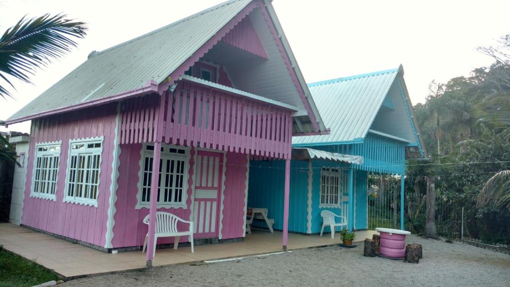 una casa rosa y azul con una silla en la parte delantera en Chalé do Gravatá, en Penha