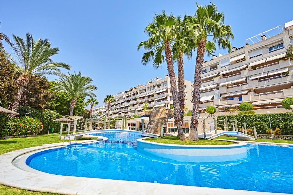 a large swimming pool with palm trees in front of a building at Beferent Riviera Blanca Golf - Playa in Alicante