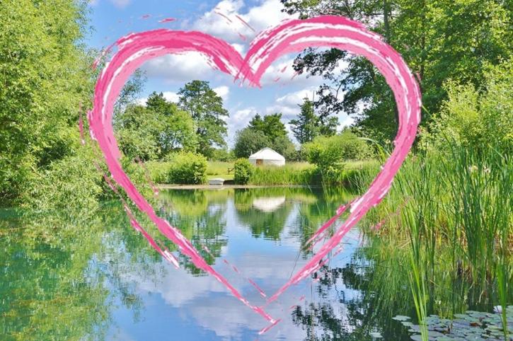 Un cuore dipinto sull'acqua di fronte a un lago di Acorn Glade Glamping a York
